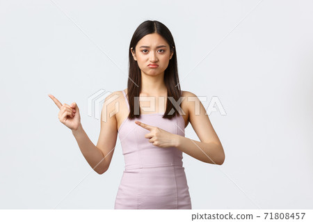Celebration, beauty and glamour concept. Disappointed and skeptical pretty asian girl in prom dress, frowning and looking upset as pointing fingers left bad product or awful party 71808457