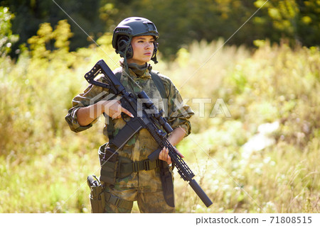 young caucasian military woman holds a gun in her hand in nature 71808515