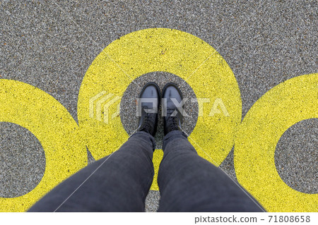 Black shoes standing in yellow circle on the asphalt concrete floor. Comfort zone or frame concept. Feet standing inside comfort zone circle 71808658