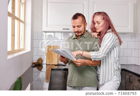 young couple managing finances, reviewing their bank accounts holding paper document young couple managing finances, reviewing their bank accounts holding paper document 71808793
