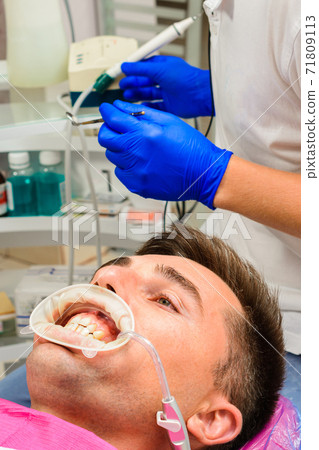The procedure at the dentist,the dentist prepares the patient and tools to remove tartar, saliva ejector and retractor in the patient's mouth. The procedure at the dentist,the dentist prepares the patient and tools to remove tartar, saliva ejector and retractor in the patient's mouth. 71809113