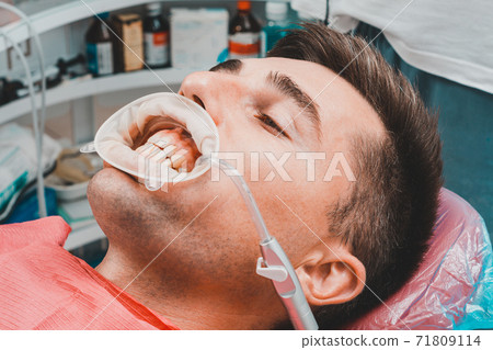 The procedure at the dentist,the dentist prepares the patient and tools to remove tartar, saliva ejector and retractor in the patient's mouth. The procedure at the dentist,the dentist prepares the patient and tools to remove tartar, saliva ejector and retractor in the patient's mouth. 71809114
