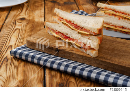 Sandwiches cut into halves on wooden cutting board with napkin 71809645