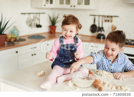 Boy and girl littered in flour in the kitchen Boy and girl littered in flour in the kitchen 71809830