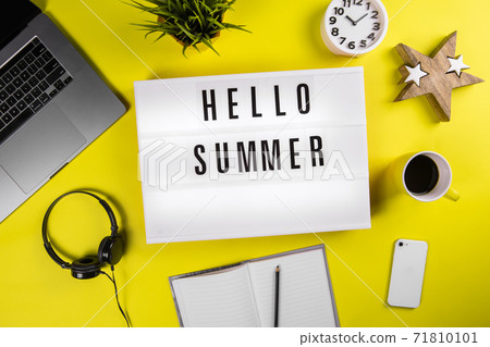 Hello Summer message on lightbox on modern yellow office desktop with laptop Hello Summer message on lightbox on modern yellow office desktop with laptop 71810101