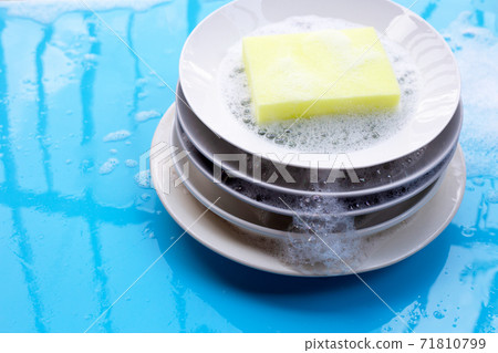 Washing dishes on wet blue background with soapy foam. 71810799