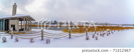 Clubhouse overlooking lake and homes against cloudy sky on a frosty winter day 71812967
