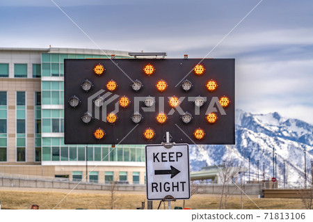 Close up of an arrow board and Keep Right sign against a modern building Close up of an arrow board and Keep Right sign against a modern building 71813106