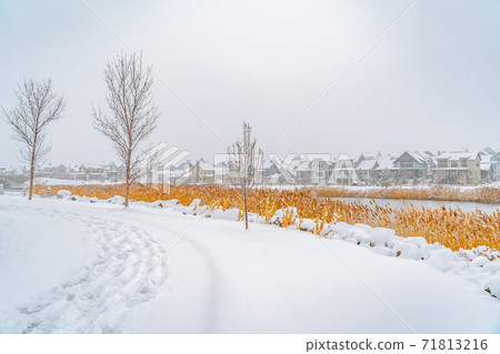 Trail on the powdery snow along Oquirrh Lake with view of homes and vast sky 71813216