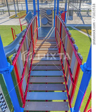 Playground equipment with a bridge and slide against vibrant green lawn Playground equipment with a bridge and slide against vibrant green lawn 71813518