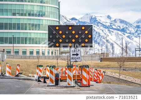 Keep Right sign underneath an arrow board surrounded by road safety poles Keep Right sign underneath an arrow board surrounded by road safety poles 71813521