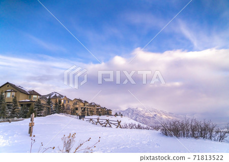 Homes overlooking a scenic snow capped mountain and vivid blue sky with clouds Homes overlooking a scenic snow capped mountain and vivid blue sky with clouds 71813522