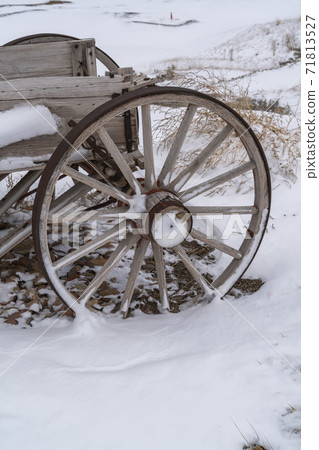 Wheel of an old wooden cart against a rocky snow covered terrain in winter Wheel of an old wooden cart against a rocky snow covered terrain in winter 71813527