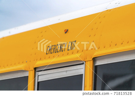 Close up of the exterior of a yellow school bus with an Emergency Exit sign Close up of the exterior of a yellow school bus with an Emergency Exit sign 71813528
