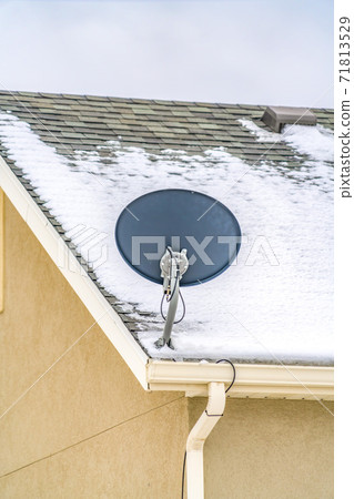 Exterior view of a home with a small satellite dish at the corner of the roof Exterior view of a home with a small satellite dish at the corner of the roof 71813529