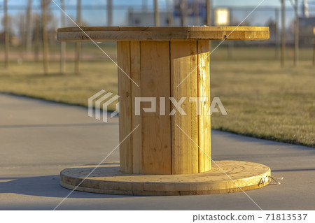 Close up of a smooth and shiny light brown wooden spool table on a sunny day Close up of a smooth and shiny light brown wooden spool table on a sunny day 71813537