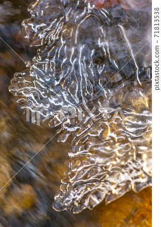 Close up of translucent frozen water on a rocky stream during winter Close up of translucent frozen water on a rocky stream during winter 71813538