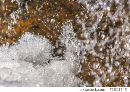 Close up of crystalline ice and brown rock covered with shiny frozen water Close up of crystalline ice and brown rock covered with shiny frozen water 71813545