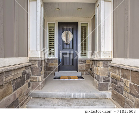 Home entrance with a gray front door in the middle of sidelights with blinds 71813608