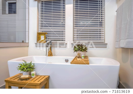 Relaxing bathroom interior with spotless white bathtub mirror and two windows Relaxing bathroom interior with spotless white bathtub mirror and two windows 71813619