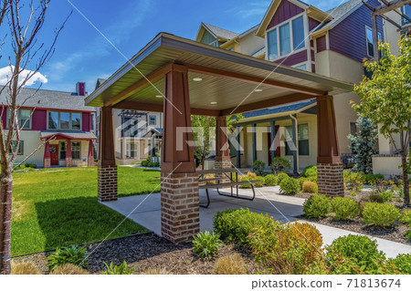Covered patio on the lawn surrounded by house under blue sky 71813674
