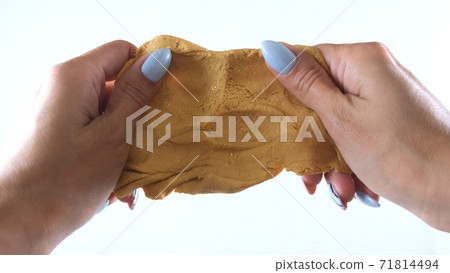 Female hands are molded from gold plasticine, developing activities for children. 71814494