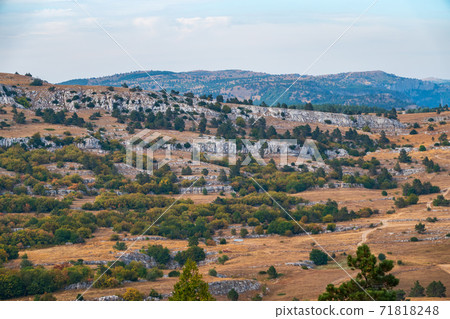 Autumn steppe landscape on a mountain plateau with low trees. Autumn steppe landscape on a mountain plateau with low trees. 71818248