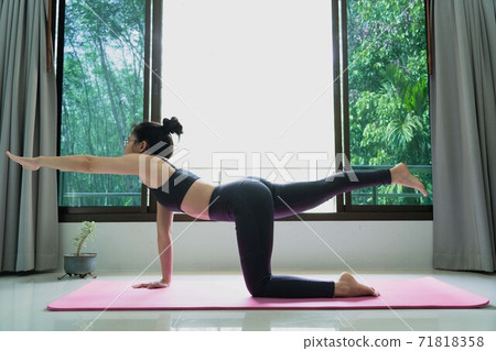 Woman Doing Exercises at home,people and healthy lifestyle concept -female wearing sportswear practicing yoga doing stretching on the mat warm up muscles for good health and weight loss Woman Doing Exercises at home,people and healthy lifestyle concept -female wearing sportswear practicing yoga doing stretching on the mat warm up muscles for good health and weight loss 71818358