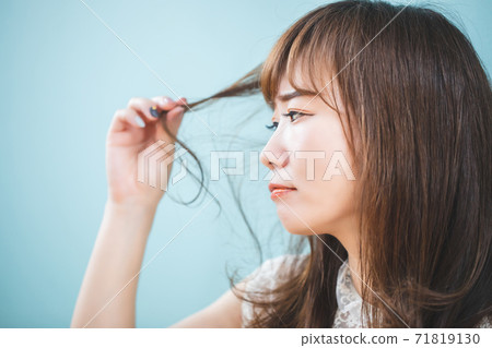 Woman looking at damaged hair 71819130