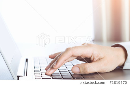 Side view of slim laptop on desk and female hand typing Side view of slim laptop on desk and female hand typing 71819570