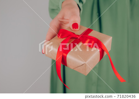 Young woman holding Christmas present box decorated with red bow. Christmas holidays and New Year celebration concept. Preparing family gifts for Christmas Young woman holding Christmas present box decorated with red bow. Christmas holidays and New Year celebration concept. Preparing family gifts for Christmas 71820436