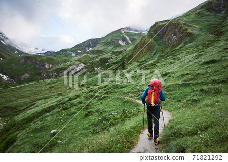 Male hiker walking down rocky mountain path. Male hiker walking down rocky mountain path. 71821292