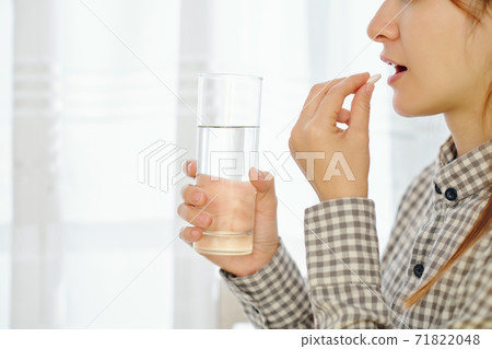 Woman taking birth control tablet 71822048