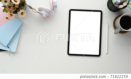 Flat lay photo of freelancer workspace with empty screen tablet, notebook, coffee cup and headphone on white table. Flat lay photo of freelancer workspace with empty screen tablet, notebook, coffee cup and headphone on white table. 71822259