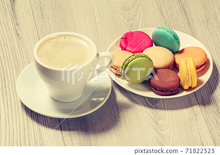 Cup of coffee and delicious macarons cakes of different color on plate 71822523