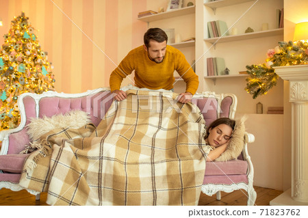 Caring husband covering his napping wife with a plaid Caring husband covering his napping wife with a plaid 71823762