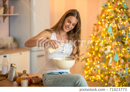 Pretty woman in white tshirt pouring milk Pretty woman in white tshirt pouring milk 71823773