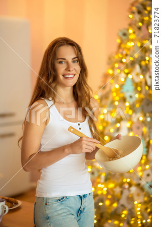 Young woman in white tshirt stirring something in a bowl Young woman in white tshirt stirring something in a bowl 71823774