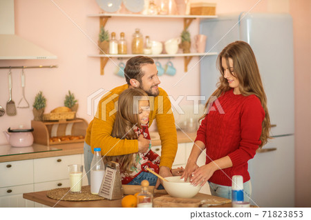 Kid and her parents cooking together in the kitchen Kid and her parents cooking together in the kitchen 71823853