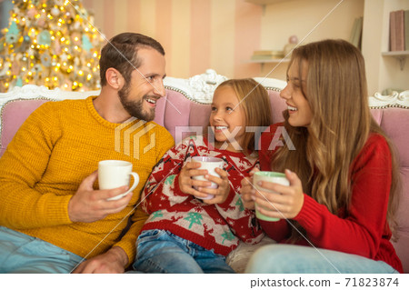 Young family sitting on the sofa and feeling comfortable Young family sitting on the sofa and feeling comfortable 71823874