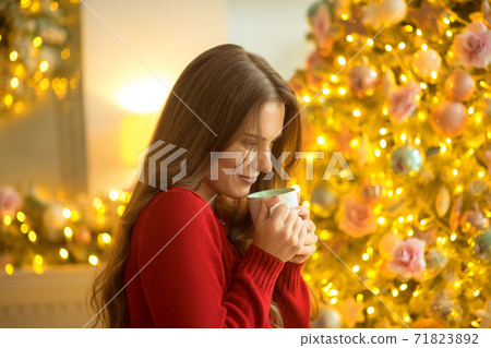 Dark-haired young woman standing with a cup and looking dreamy Dark-haired young woman standing with a cup and looking dreamy 71823892