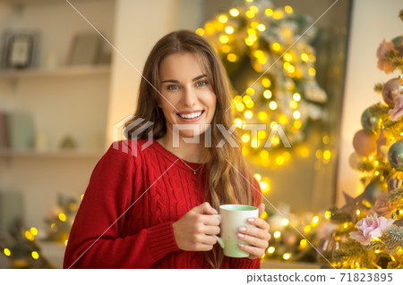 Dark-haired young woman standing with a cup and smiling Dark-haired young woman standing with a cup and smiling 71823895