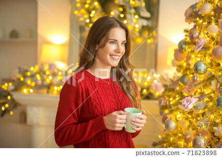 Dark-haired young woman standing with a cup and smiling Dark-haired young woman standing with a cup and smiling 71823898