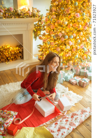 Dark-haired young woman packing christmas gifts and looking happy Dark-haired young woman packing christmas gifts and looking happy 71823927