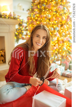 Dark-haired young woman packing christmas gifts and looking happy Dark-haired young woman packing christmas gifts and looking happy 71823928