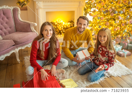 Young family sitting on the floor and packing christmas gifts Young family sitting on the floor and packing christmas gifts 71823935