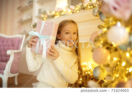 Long-haired cute girl holding a christmas gift Long-haired cute girl holding a christmas gift 71824003