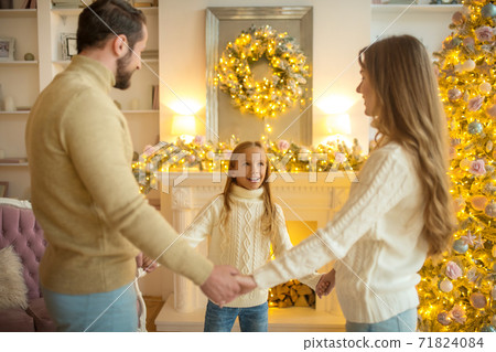 Happy family standing near christmas tree and holding hands Happy family standing near christmas tree and holding hands 71824084