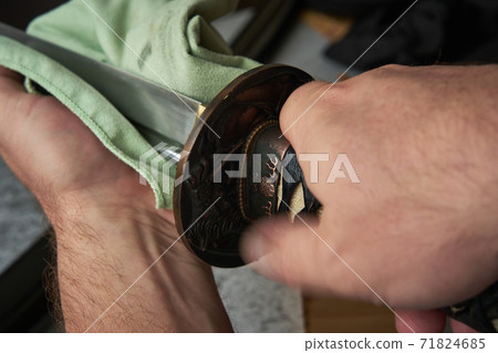 Man cleans blade of traditional Japanese katana sword 71824685