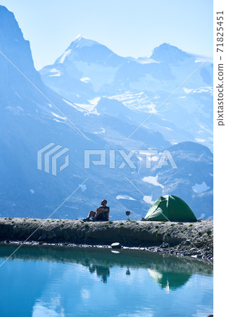 Male tourist enjoying mountains scenery near tent. Male tourist enjoying mountains scenery near tent. 71825451